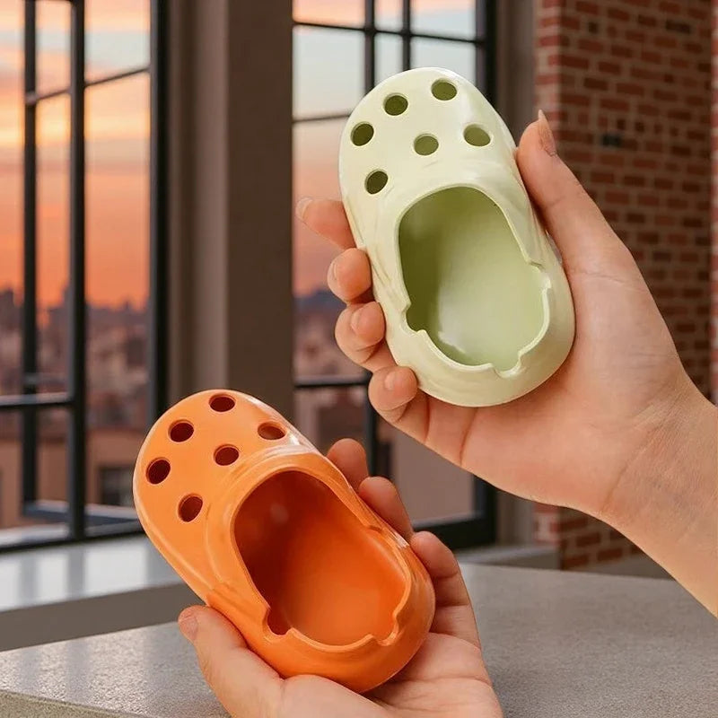 two plastic croc-shaped ashtrays in different colors (orange and off-white)
