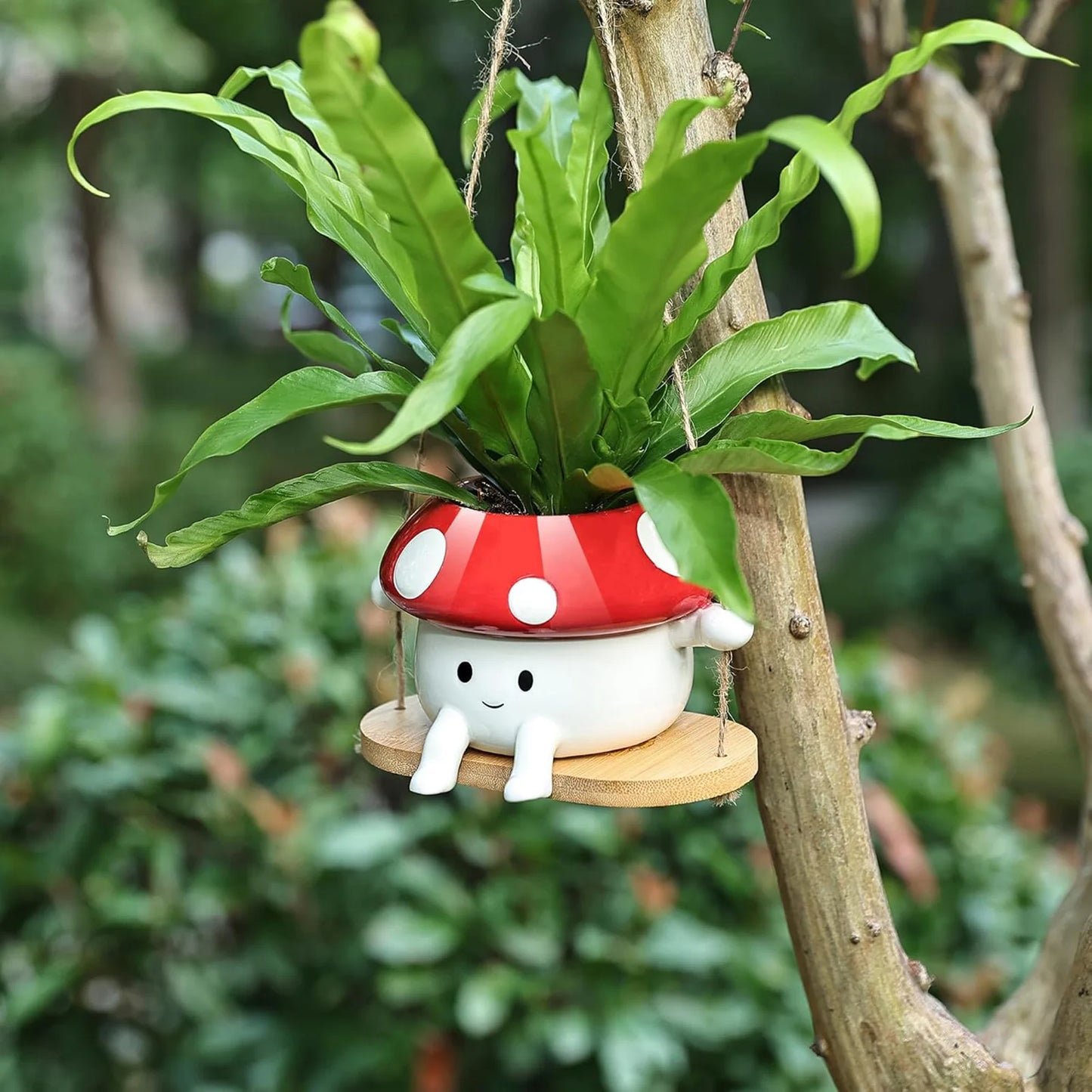 Plants in a mushroom-shaped pot hanging on a tree branch with a blurred green background