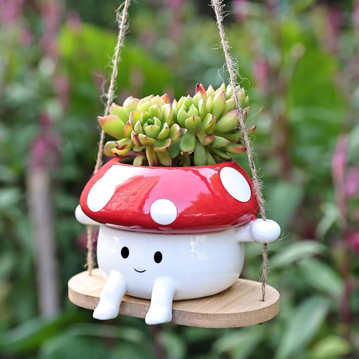 Mushroom-shaped planter with succulents on a swing against a blurred green background